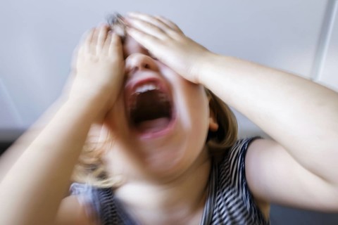 Symbolic photo on the subject of tantrums in children (staged scene) . A little girl holds her