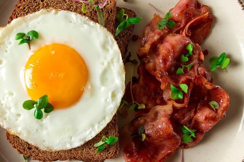 Breakfast, fried egg with bacon, micro-green, on a light background, no people, selective focus