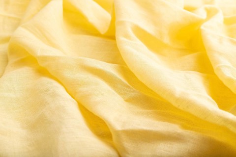 Fragment of yellow linen tissue. Side view, natural textile background and texture. wave concept,