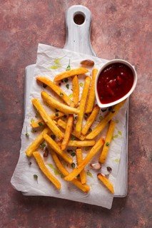 Fried French fries, in a paper bag, on an abstract background, no people, rustic