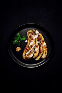 Fried eggplant slices, with white sauce, on a black background, top view, vertically, without