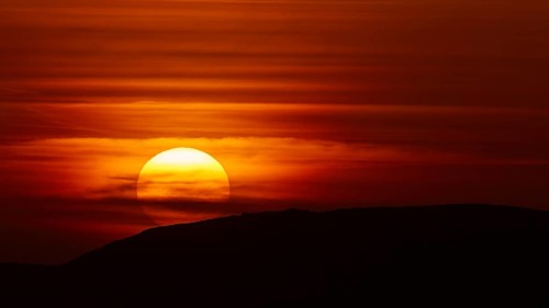 A fascinating sunset, where the setting sun bathes the sky in shades of red and disappears behind a