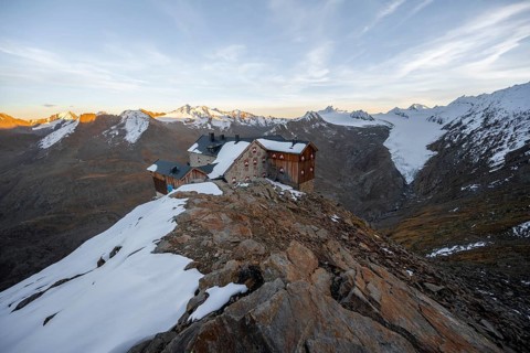 Snow-covered mountain landscape, mountain hut Ramolhaus in autumn with snow, at sunset, view of