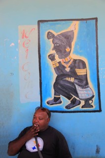South Ethiopia, in Dimeka, local man sitting in front of a painting in a cafe and smoking a