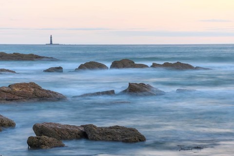 The lighthouse of the barges on the horizon seen from the beach of Sauveterre. Les Sables d'Olonne,