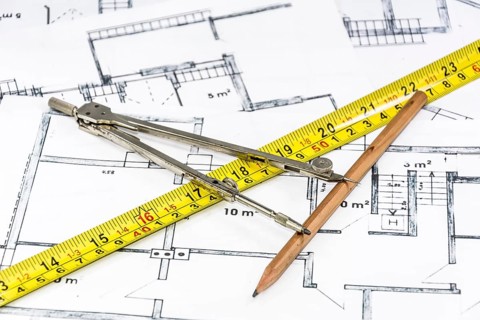 Compass calipers and pencil lying on construction plan