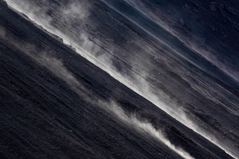 Smoke rises diagonally from the slope of a volcano
