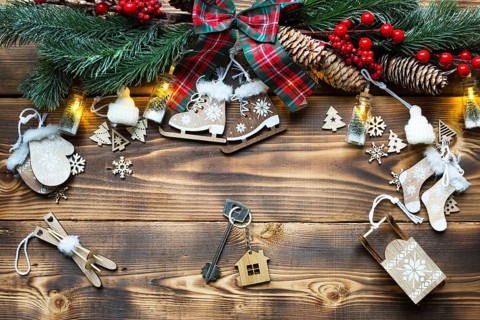 House key with keychain cottage on a festive eco friendly, natural background with Christmas tree.