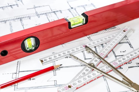 Spirit level, pencil, yardstick and compass calipers on a construction plan