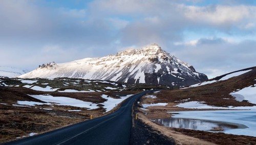 Typical Icelandic snowy nature mountain landscape and empty road near Arnarstapi area in