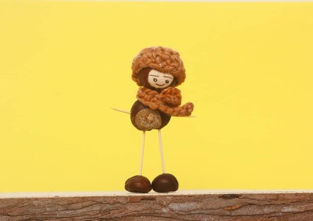 Chestnut figure with hat and scarf in front of yellow background in the studio