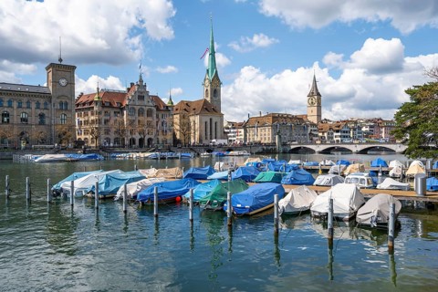 Boats at the jetty in the river Limmat, towers of Fraumünster and St Peter, Old Town, Zurich,