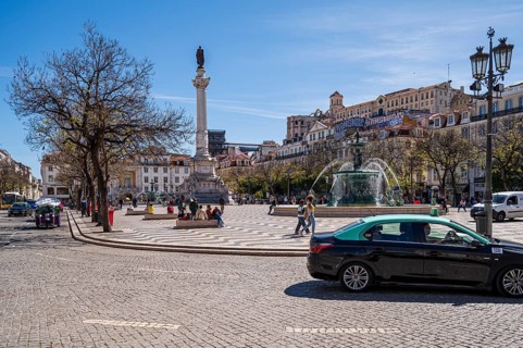 Praça do Rossio in Lisbon, Spacious city square with cars, statue and lively atmosphere under a