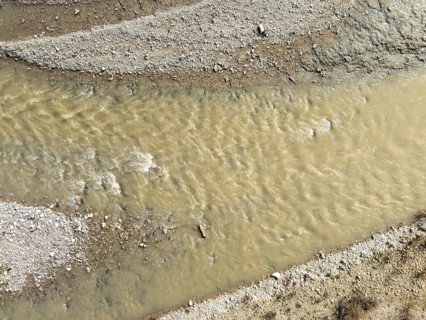 Muddy water flowing in the arda river near mignano val tolla in piacenza, italy, creating small