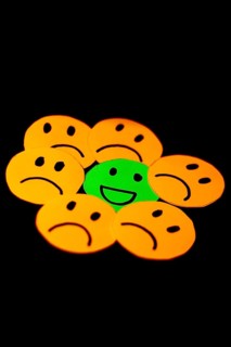 Paper cutouts of sad smileys surrounding a happy smiley. concept of positivism, social problems,