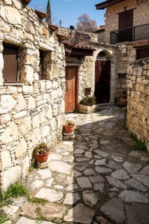 Stoned footpath crossing a traditional village. Stoned houses with wooden doors. Vintage