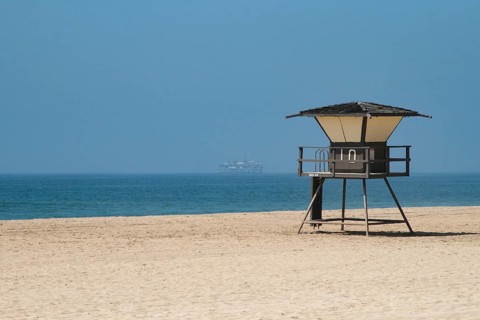 Oil rig near beach with lifeguard tower
