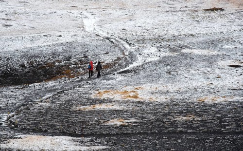 Unrecognized people trekking on a curved nature trail covered in snow in Iceland
