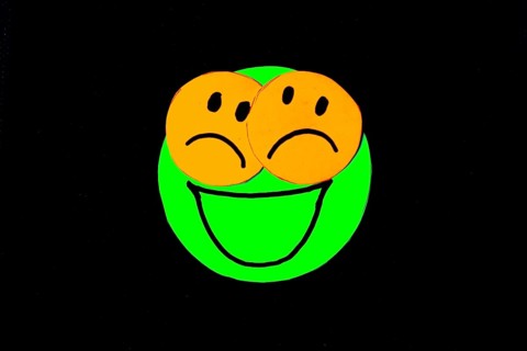 Paper cutouts of circles with faces drawn on black background. concept of pretending to be happy
