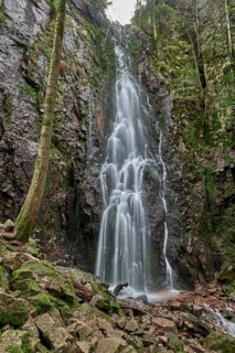 Burgbach Waterfall in coniferous forest falls over granite rocks into the valley near Bad