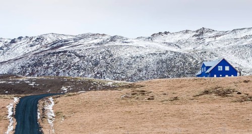 Icelandic landscape with blue chalet farm house in Reykjanes peninsula, Mountains covered in snow