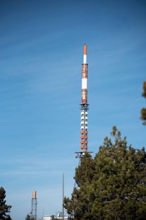 Communication tower on a building with 4G 5G antenna and satellite dish against blue sky. Mobile