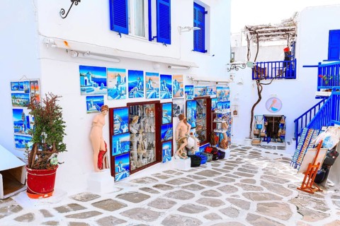 Mykonos, Greece, April 23, 2019: Famous island street view with white houses and souvenir gift shop