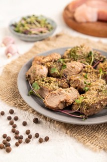 Stewed turkey fillet with garlic and sprouts of radish on white wooden background and linen textile