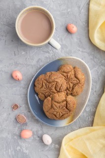 Homemade oatmeal cookies with a cup of cocoa and a yellow textile on a gray concrete background.