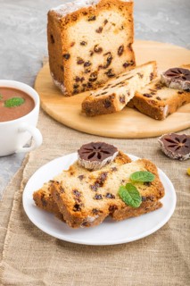 Homemade cake with raisins, dried persimmon and a cup of hot chocolate on a gray concrete