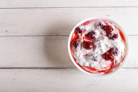 White plate with greek yogurt and strawberry jam on white wooden background. top view. copy space