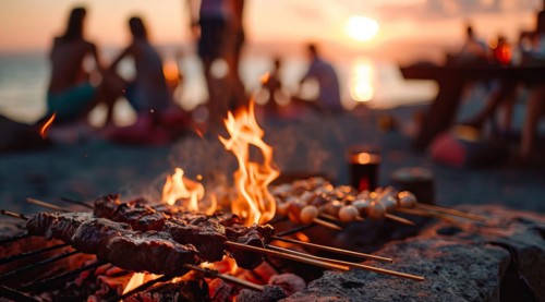 Barbecue BBQ family picnic party on the beach with skewers of meat and meat steaks over charcoal,