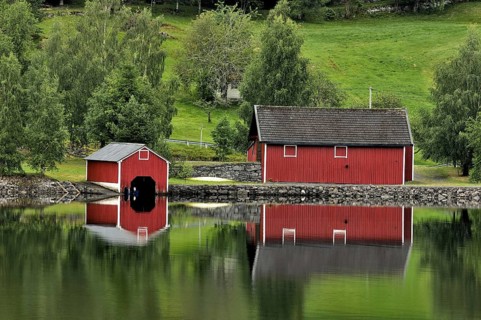 Red wooden boathouses at lake in Norway, Scandinavia