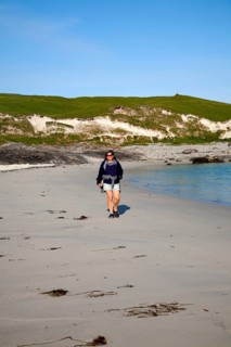 Woman walking on sandy beach at Bagh a Deas, South Bay, Vatersay island, Barra, Outer Hebrides,
