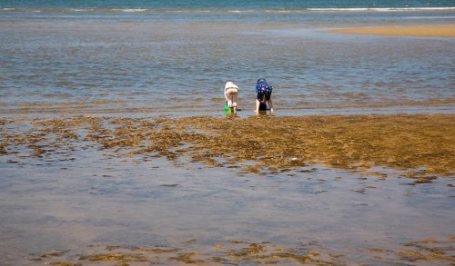 Two children playing with buckets in the sea at Hunstanton, north Norfolk coast, England, United