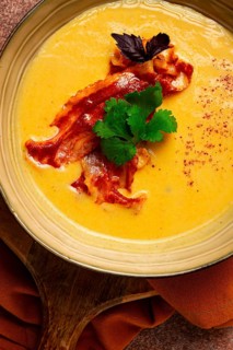 Pumpkin cream soup, curry, fried bacon, bruschetta chips, micro-greens, top view, no people