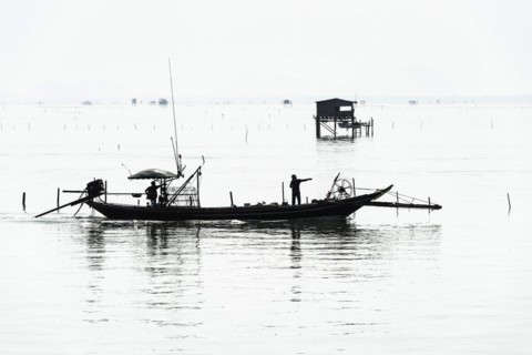 Traditional wooden huts of fishermen in the Gulf of Thailand in the morning haze, fishing boat,