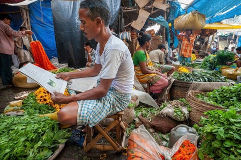 Vendor reading newspaper, fruit, vegetable and flower market, Howrah Bridge, Kolkata or Calcutta,