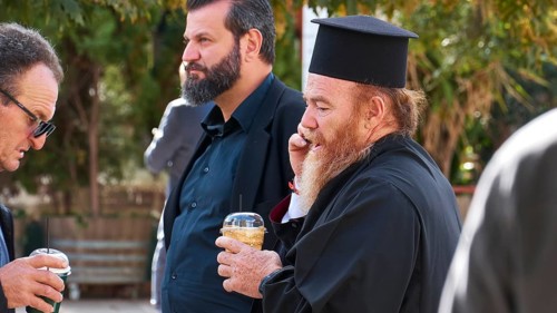 Men, including an Orthodox priest, drinking and chatting outdoors, visit of German President