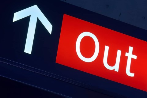 Red exit sign with white arrow pointing upwards, illuminated in a dark environment, Toronto