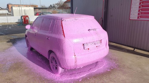 A car is covered in pink foam and is parked in a car wash, Skoda Fabia, Ilsede, Peine district,
