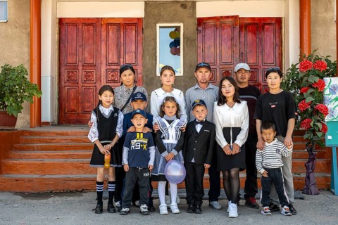 Family and school children, group posing in front of the school on the first day of school,