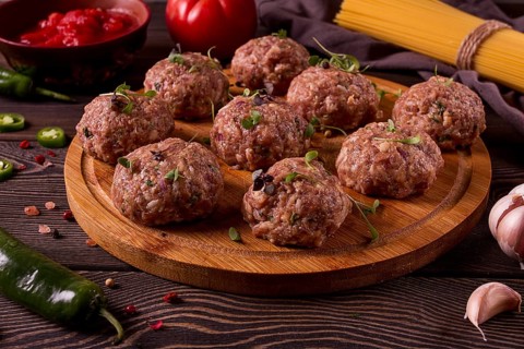 Raw meatballs, with micro greenery, with spices and ingredients, on a wooden table, homemade,