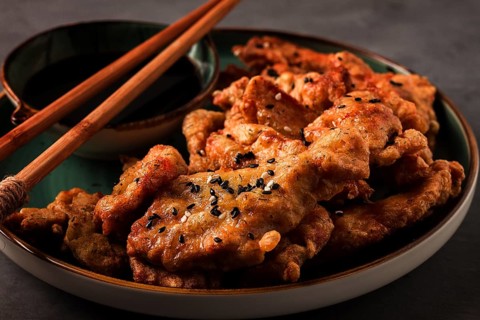 Fried meat in batter, deep-fried, with sesame seeds, and soy sauce, on a gray table, there are no