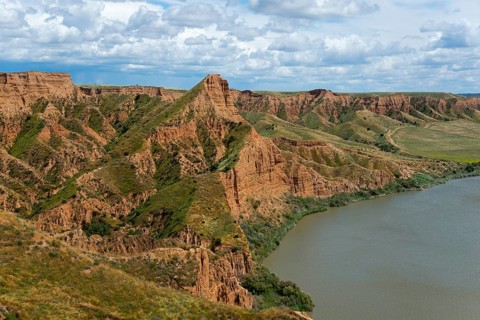 Eine weite Sicht auf einen grünen und braunen Canyon, der an einen ruhigen Fluss grenzt, Barrancas