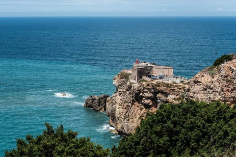 Lighthouse on the coast, on cliffs, surrounded by sea and forest, blue sky in the background, Fort