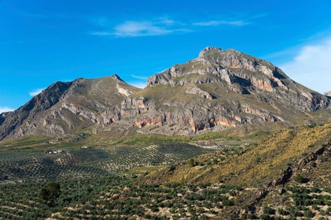 Large mountains and green hills under a clear blue sky, a picturesque example of natural beauty,