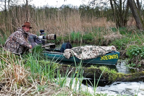 A canoe with camouflaged camera in a swamp, surrounded by vegetation and quiet nature, boat of a