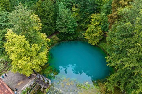 Blautopf Blaubeuren, source of the River Blau in a landscape with forest. Karst spring, geotope and