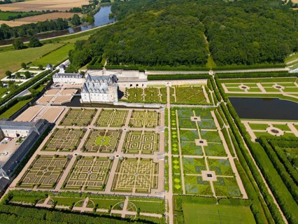 Aerial view of a castle with formal, geometric gardens consisting of labyrinths, ponds and